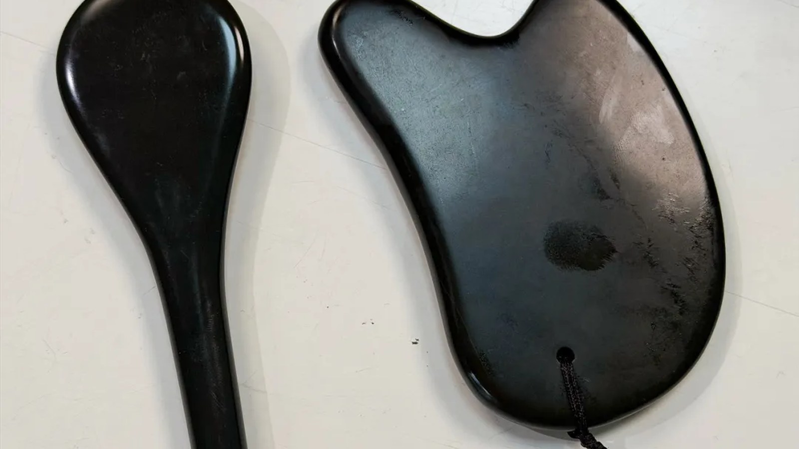 Dark smooth gua sha tools displayed on a clean tabletop