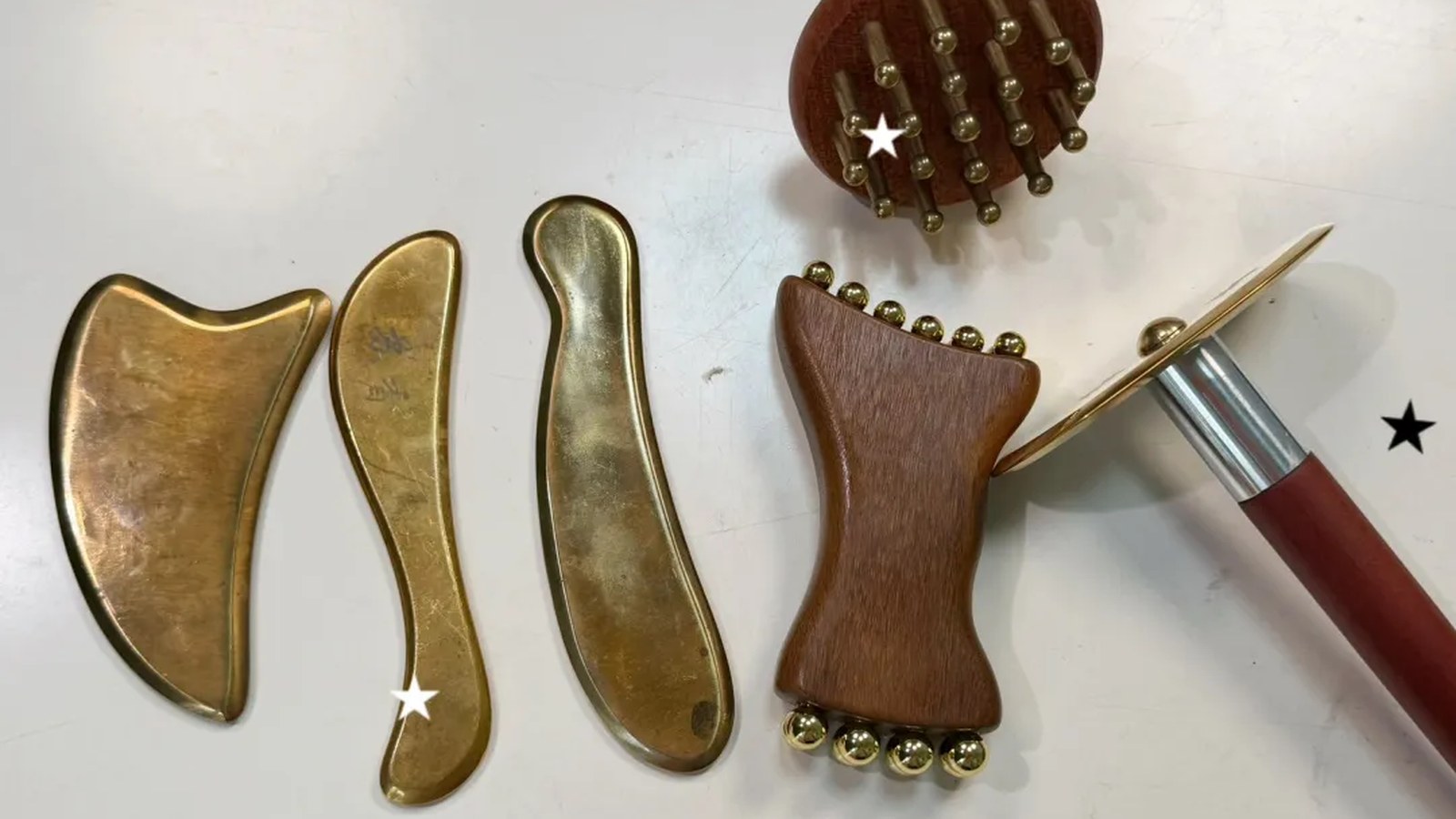 A set of brass and wooden gua sha tools arranged for material comparison