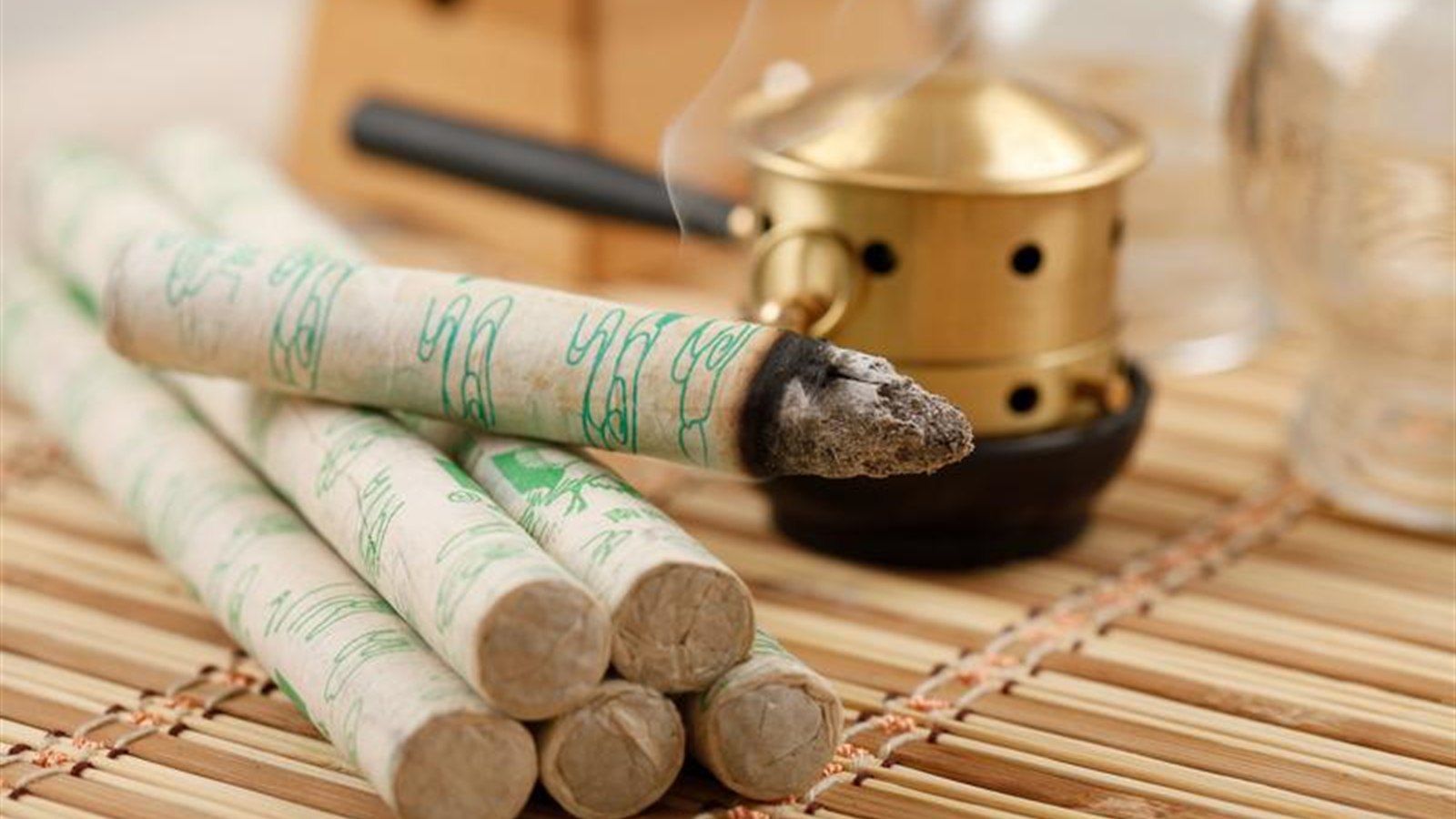 Moxa sticks and a small warming holder arranged on a bamboo mat