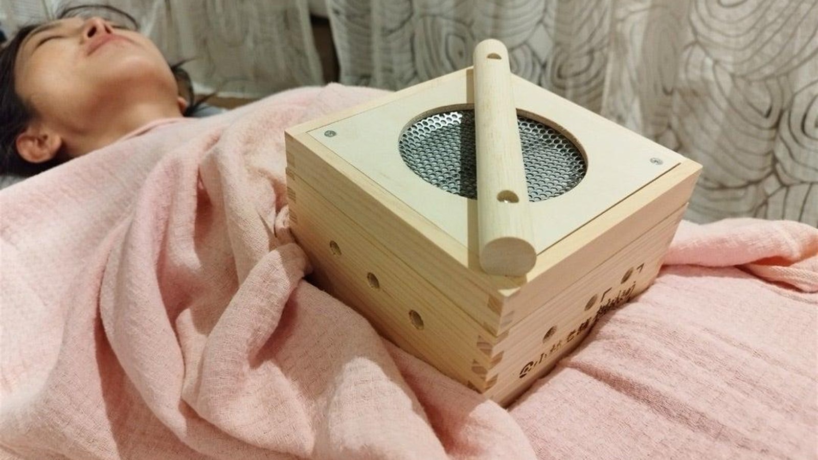 Wooden moxa box placed over the abdomen for broad warmth