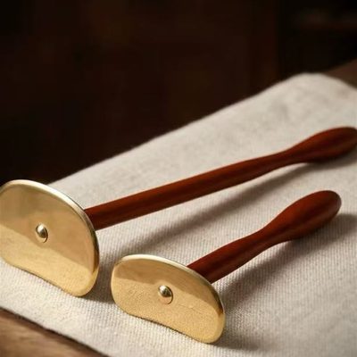 Long and short brass Gua Sha tools on linen