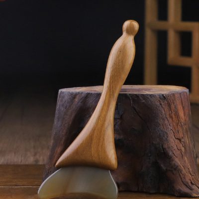 Single natural horn massage stick with wooden handle on wood surface