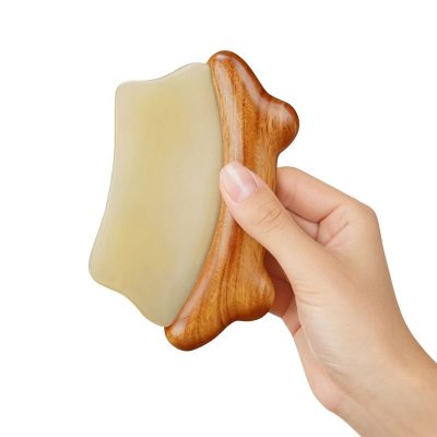 Natural horn and sandalwood Gua Sha massage board in hand